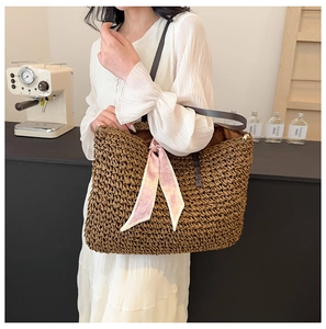 Detail of large woven straw beach tote with pink heart scarf and leather straps