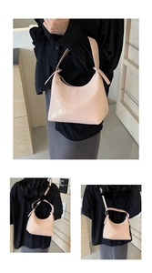 Detail of pink half-moon underarm bag with glossy shimmering texture and adjustable strap