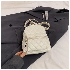 Close-up of white quilted leather mini backpack with golden zipper and fine stitching