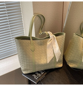 Detail of light green woven tote bag featuring leather braiding and printed silk scarf