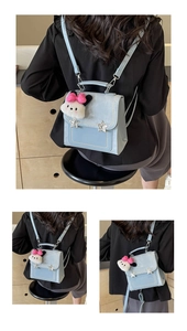 Detail of light blue patent leather backpack featuring star studs and plush charm