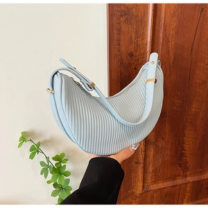 Macro detail of a light blue pleated crescent shoulder bag with golden hardware