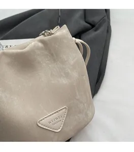 Detail of minimalist beige bucket bag featuring soft textured fabric and silver chain