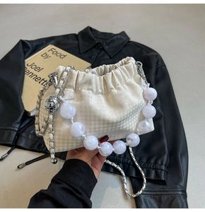 Detail of cream pleated cloud bag with houndstooth pattern and large pearl bead handle