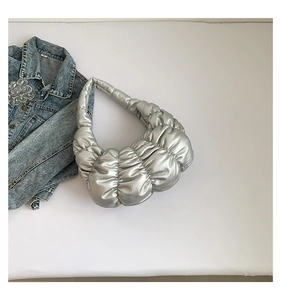Detail of silver metallic pleated cloud bag with soft puffer texture and integrated handle