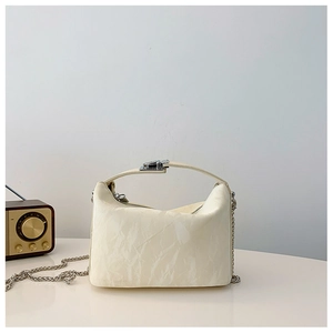 Detail van de crème crossbodytas met rimpeltextuur en zilveren kettingriem