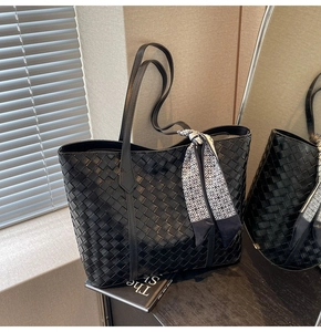 Detailed view of black woven leather tote bag with stylish patterned silk scarf on handle