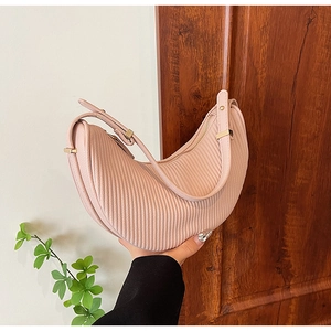 Detailed close-up of pink dumpling bag with vertical stripes and golden buckle detail