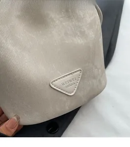 Detailed view of grey textured fabric on bucket bag featuring a stitched triangular logo patch