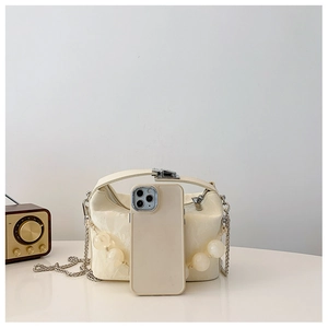 Detail van crème PU-lederen handtas met decoratieve kralen en zilveren sluiting met telefoon