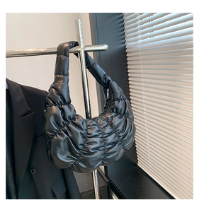 Detail of black pleated cloud bag with leather texture hanging on a silver hanger