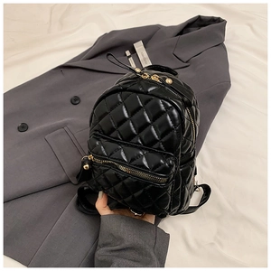 Detail of black quilted mini backpack featuring glossy PU leather and gold zipper hardware