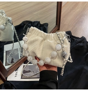 Detail of pleated houndstooth cloud bag with chunky pearl handle and silver chain strap