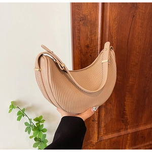 Detail of cream crescent bag featuring vertical textured pleats and gold metal hardware