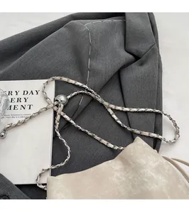 Close-up of beige drawstring bucket bag with silver chain and adjustable metal ball buckle