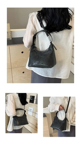 Detail of the black textured shoulder bag with glossy finish and silver metal buckle