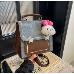 Detail of blue denim and brown leather handbag with star buckle and pearl trim