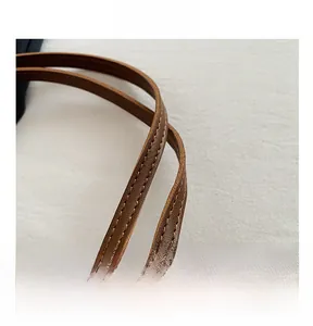 Detailed close-up of the durable brown leather shoulder strap with reinforced stitching