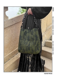 Detail of moss green tote with wooden bead handles and abstract ink-wash pattern
