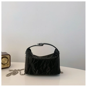 Detail van glanzende zwarte geplooide tas met zilveren gesp en metalen kettingriem