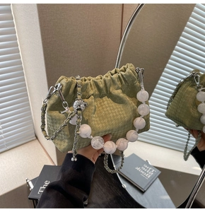 Macro detail of mint green drawstring bag with marble bead handle and chain strap