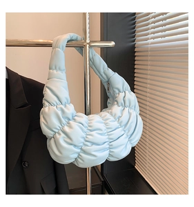Close-up of light blue quilted pleated cloud bag with metallic silver zipper detail