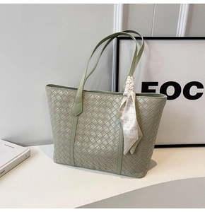 Detail of light green woven leather tote bag featuring a decorative printed silk scarf
