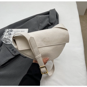 Detail of creamy white pleated leather texture and gold buckle on stylish shoulder bag