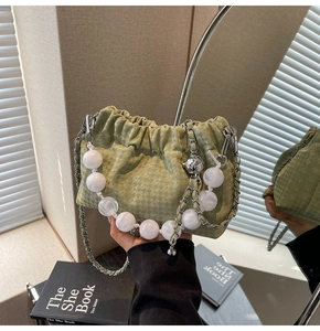 Detail of green houndstooth bag with white pearl handle and silver chain strap close-up