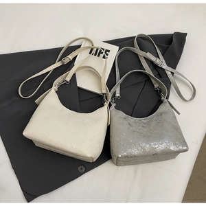 Detailed view of minimalist hobo bags in cream and metallic silver with cracked texture