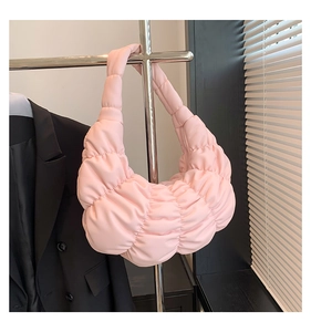Detail of light pink pleated hobo bag featuring soft ruched texture and crescent shape