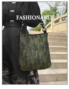 Close-up of moss green tote with embroidered texture and dark wooden bead handles