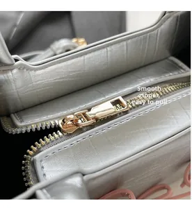 Close-up of smooth gold-tone zipper on silver metallic leather tote handbag