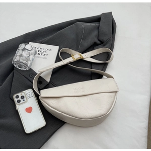 Detail showing pleated texture and embossed logo on ivory half-moon crossbody bag