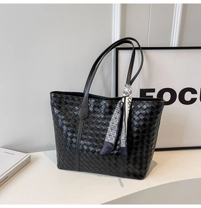 Detailed close-up of a black woven tote bag featuring a chic checkered silk scarf accent