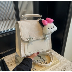Detail showing cream leather square bag with silver star buckles and plush charm