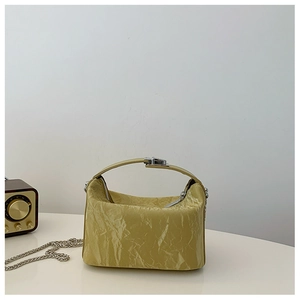 Detail van lichtgele glanzende crossbodytas met plooistructuur en zilveren ketting