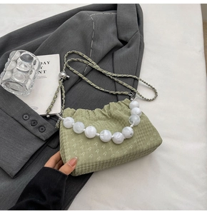 Close-up of pale green pleated cloud bag with marble bead handle and chain strap