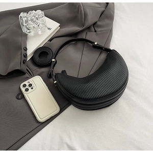 Detail view of black pleated dumpling bag with adjustable wide strap and gold hardware