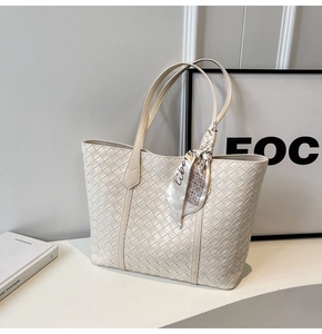 Macro detail of white woven leather tote bag featuring a decorative silk scarf on handle