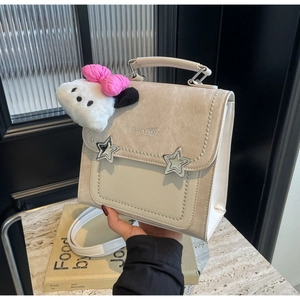 Close-up of cream canvas and PU leather bag with star charms and plush puppy pendant