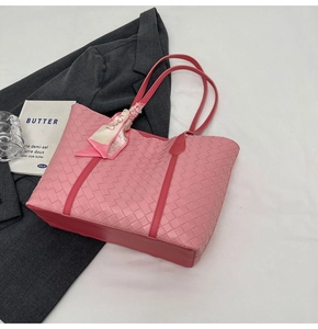 Close-up of pink woven tote bag with smooth leather handles and floral silk scarf detail