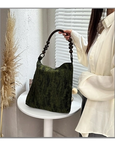 Detail of moss green embroidered tote with dark wood bead handle and woven texture