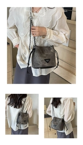Detail of grey bucket bag showing drawstring closure and woven leather chain strap
