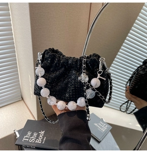 Detail of black pleated cloud bag with star patterns and large marble bead handle