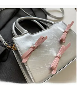 Detail of silver tote bag with pink bows, pearl accents and square embossed texture