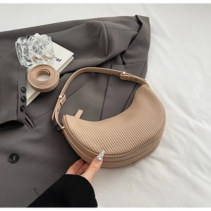 Detailed view of the vertical pleated texture on a beige crescent-shaped crossbody bag