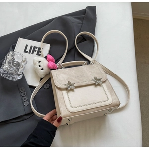 Detail view of beige multi-way backpack with silver stars and plush kitty charm