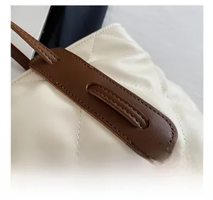 Close-up of white quilted rhombus pattern and fine stitching on a leather shoulder bag