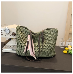 Detail of green woven tote bag with pink heart scarf and brown shoulder straps